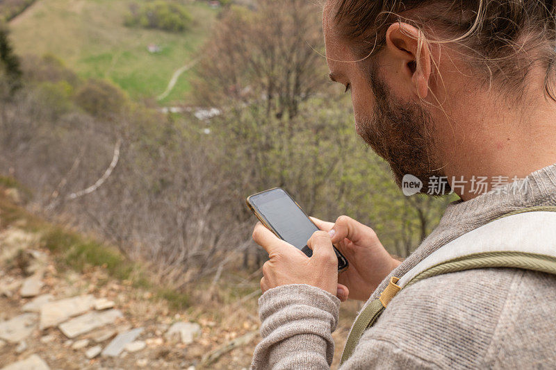 徒步旅行者在山路上使用手机