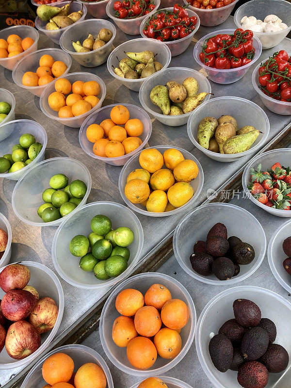 绿色食品店展示的图片称好并放在塑料碗里的新鲜水果，包括梨、番茄、草莓、酸橙、牛油果和橙子，高架视图、Covid-19法规、高架视图