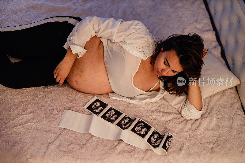 孕妇在床上抱着超声波扫描图像