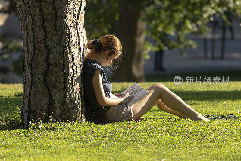 一个年轻的女人在西班牙马德里的雷蒂罗公园看书。