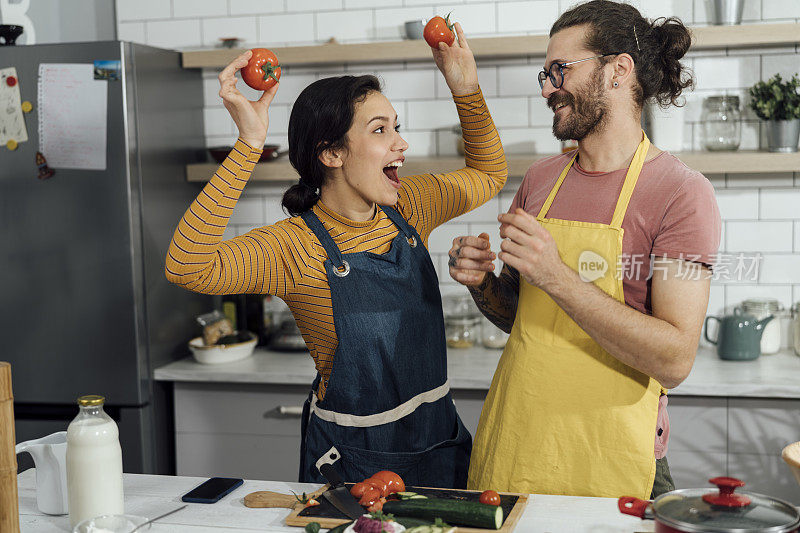 幸福的年轻夫妇在家里准备美味的食物。库存图片