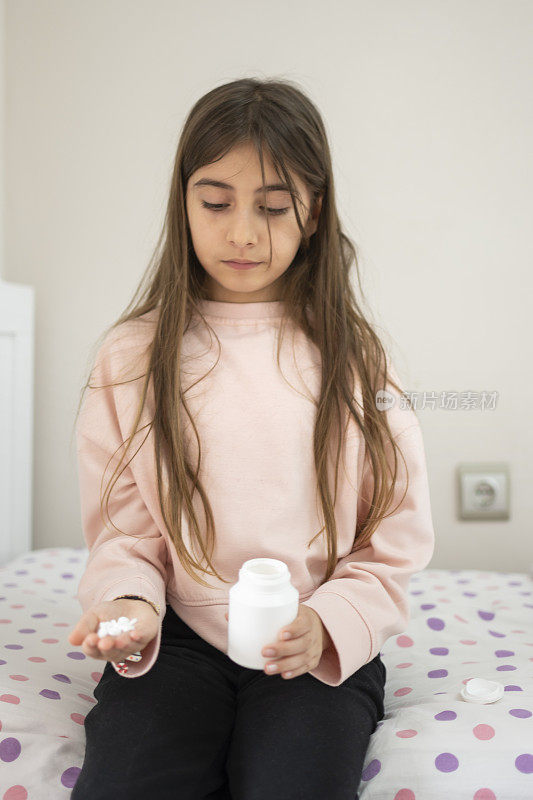 可爱的女孩吃着塑料杯里的糖和酸糖