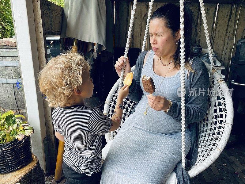 怀孕的母亲和正在吃冰激凌的儿子