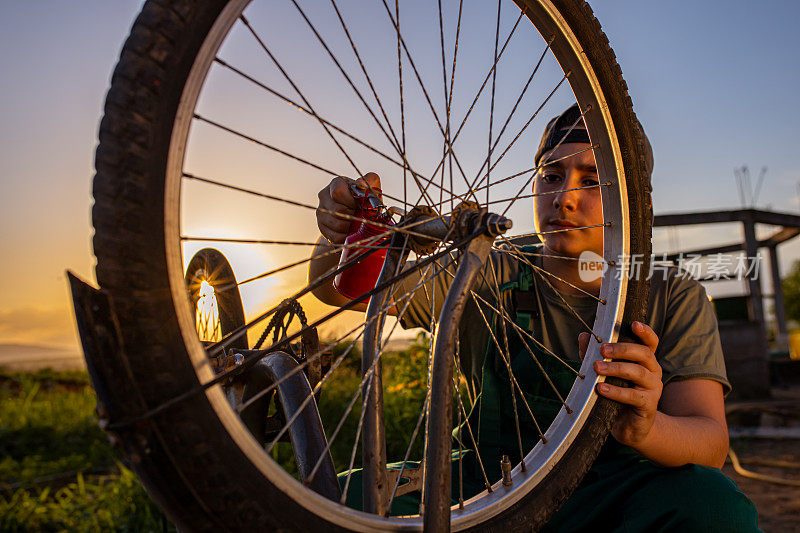 一名十几岁的男学员在户外自行车修理店给自行车的链条上油