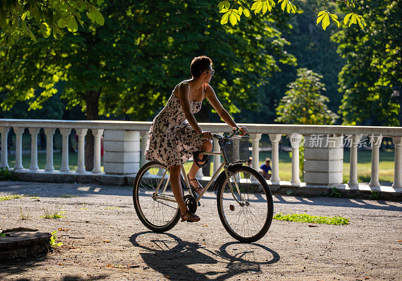 年轻的运动的女人有一个骑自行车在阳光灿烂的夏天晚上