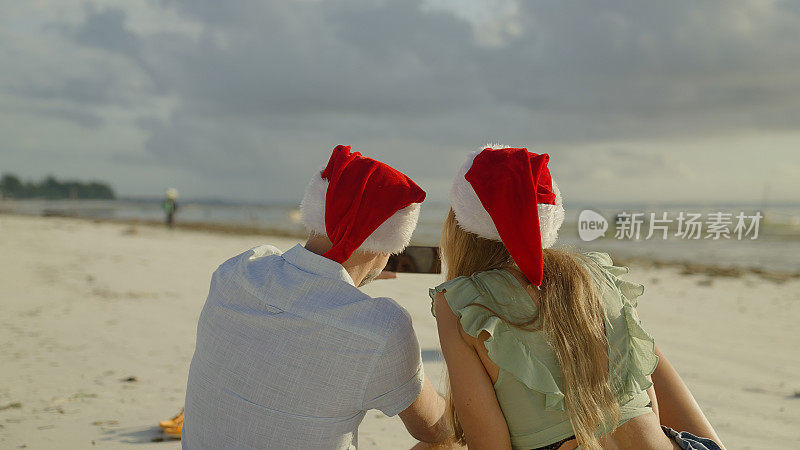 来自热带海滩的夏日圣诞问候。情侣们通过视频通话庆祝圣诞节。后视