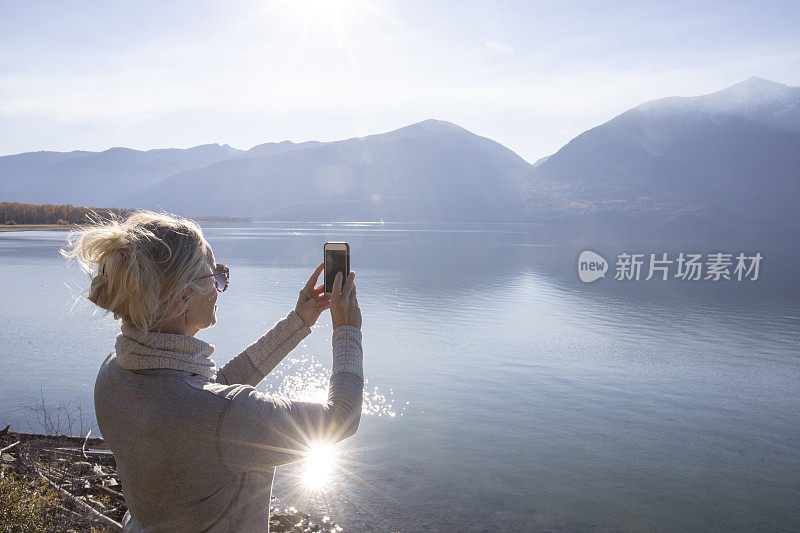 一名女子在山间湖泊上使用智能手机