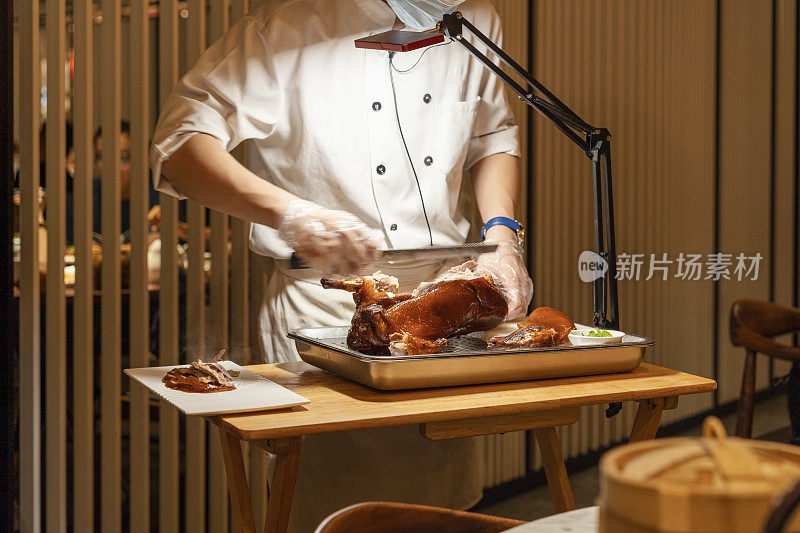 在餐馆的厨房里，厨师正在切美味的北京烤鸭