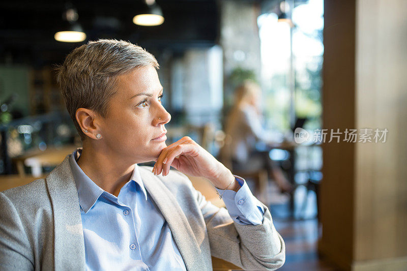 中年女商人的肖像在咖啡店放松和沉思。