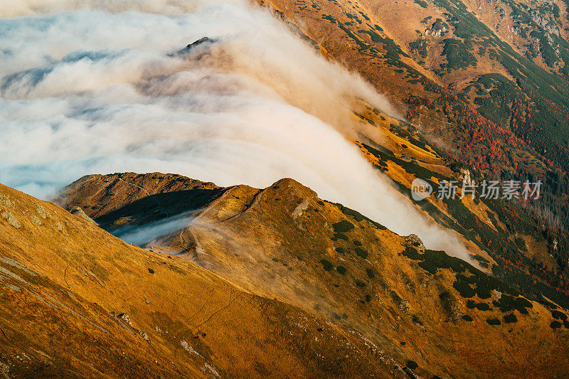 塔特拉山脉和阳光的秋景。云朵飘浮于山峰之上