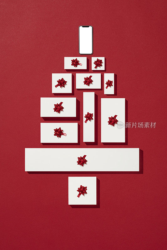智能手机模型与白色礼品盒安排作为圣诞树在红色背景