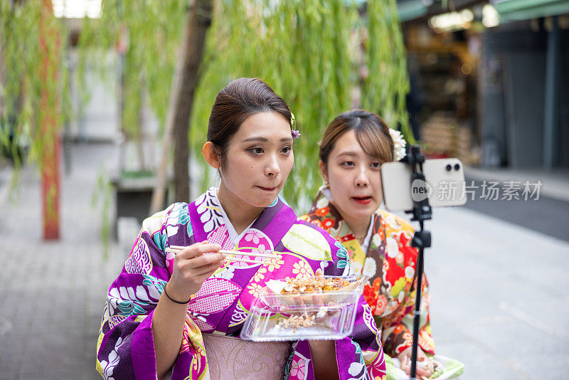 穿着和服的年轻女性在观光景点拍摄美食视频报道