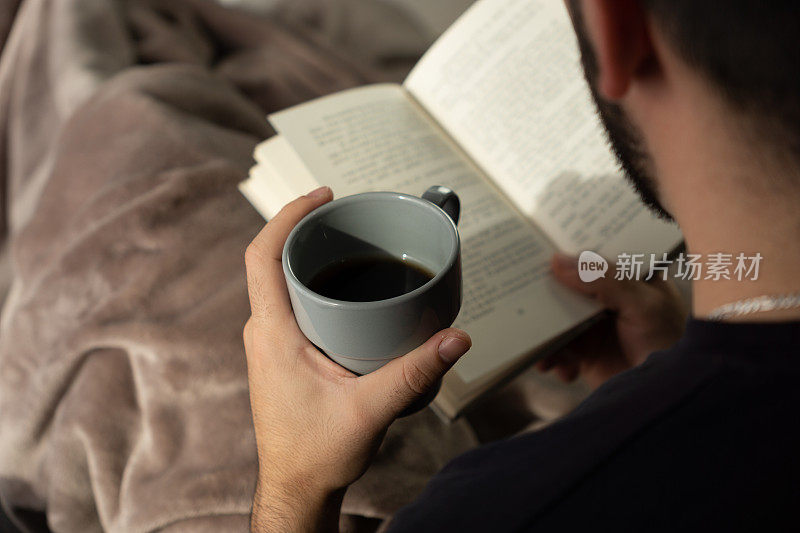 男人一边喝咖啡一边看书