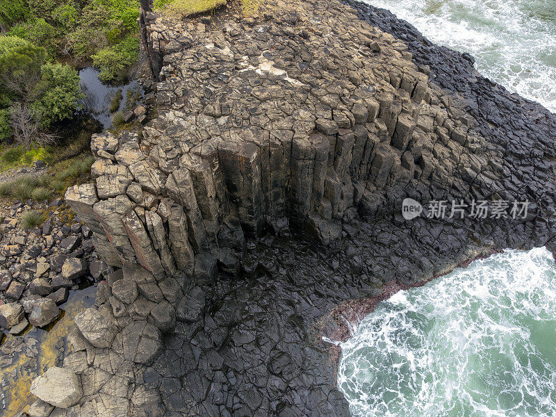 航拍海浪在玄武岩火山柱上破碎，背景与复制空间