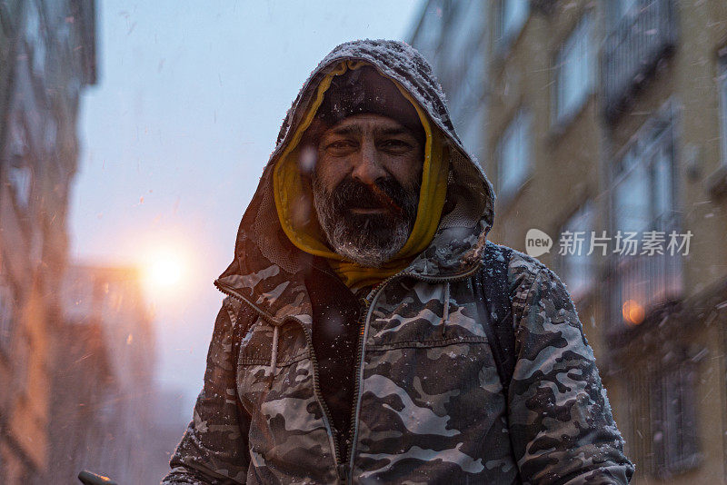 冬天，满脸胡须的中年男子在下雪的日子里在伊斯坦布尔街头的肖像。