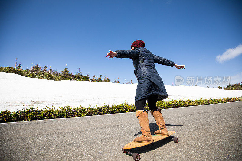 女滑板沿着高高的雪墙的山路