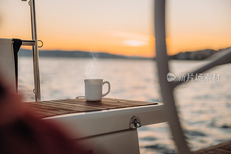 清晨的帆船甲板上，杯中有茶，杯中有烟