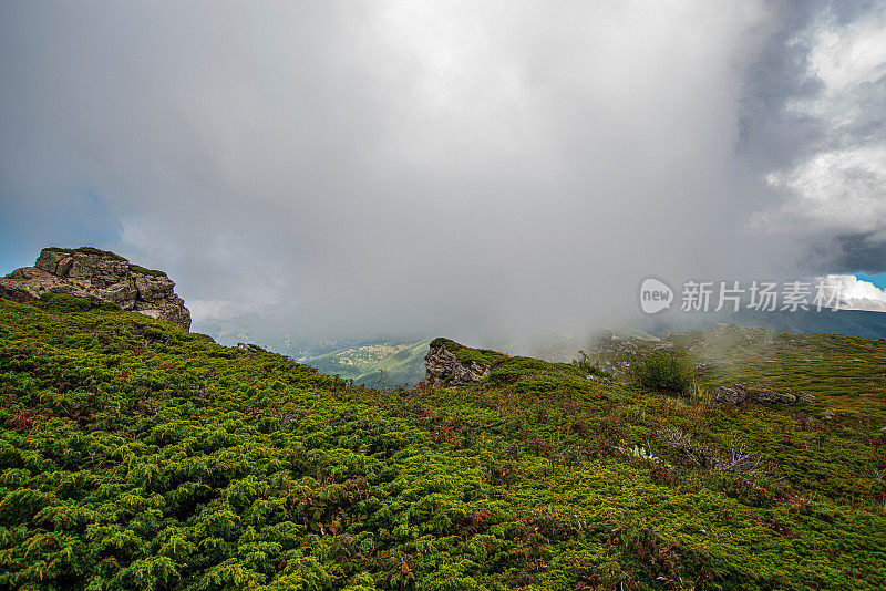 在一个阳光明媚的夏日里，有美丽的山峦和岩石景观。