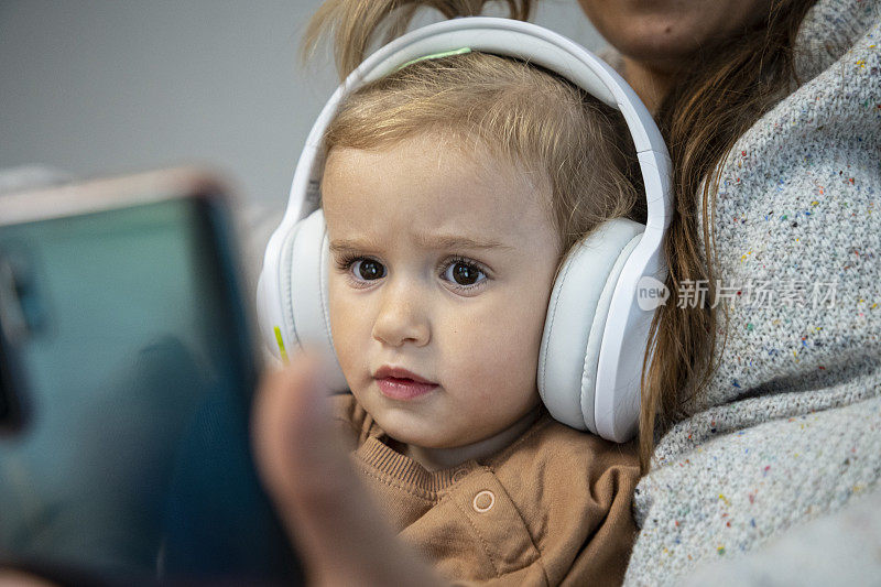 妈妈和孩子在沙发上用手机看电视。