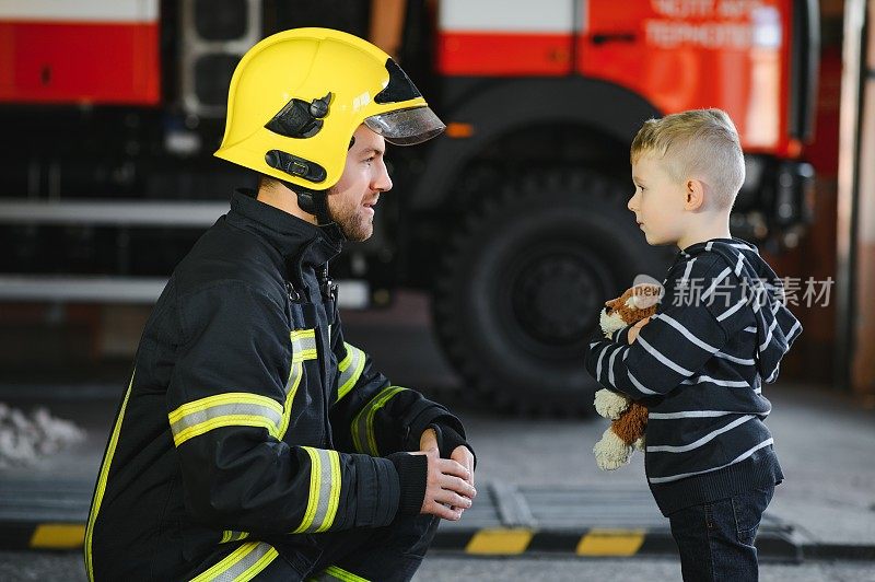 获救的小男孩和消防员站在消防车附近的肖像。消防队员在灭火作业。
