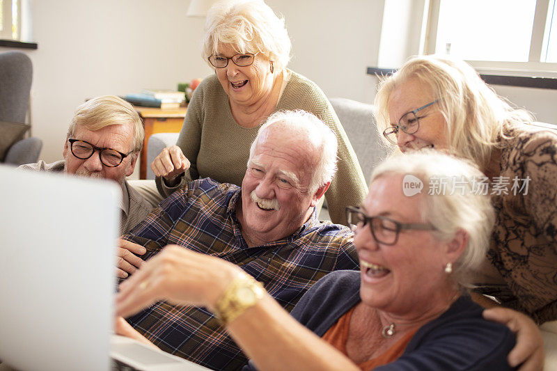 一群高级朋友一边用笔记本电脑一边笑
