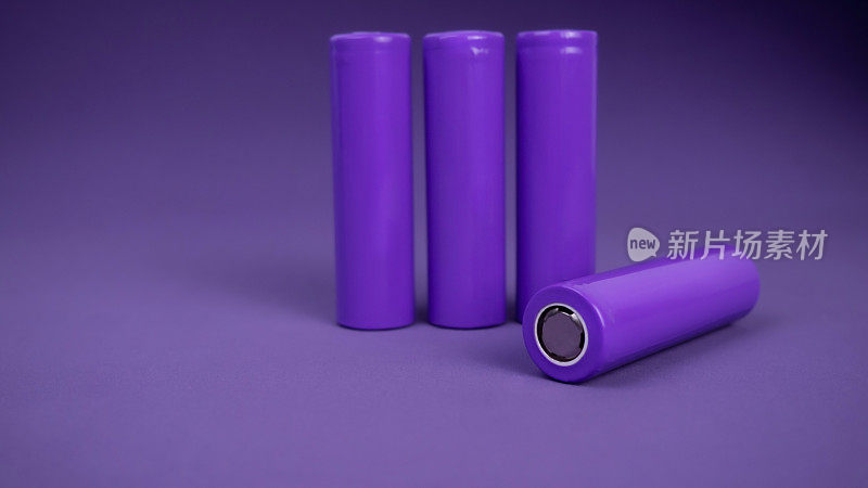 电池。圆柱形电池，18650型，紫色背景。用于电器和设备的可充电锂离子电池。