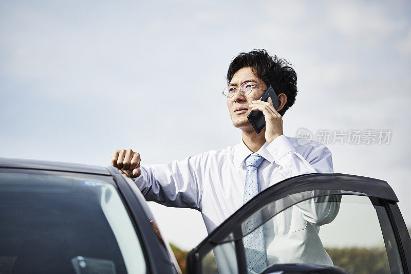 一个男人站在他的车旁边打电话