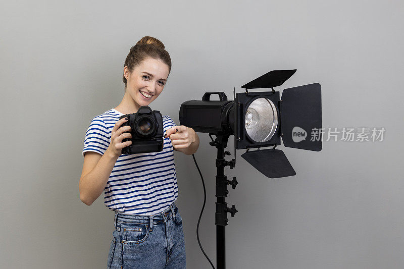 女子拍照，手持相机，使用照明设备，指向相机。