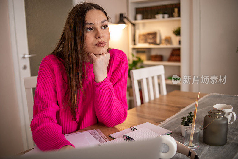 一位年轻的女学生坐在客厅里，用笔记本电脑或平板电脑为即将到来的考试或高考做准备
