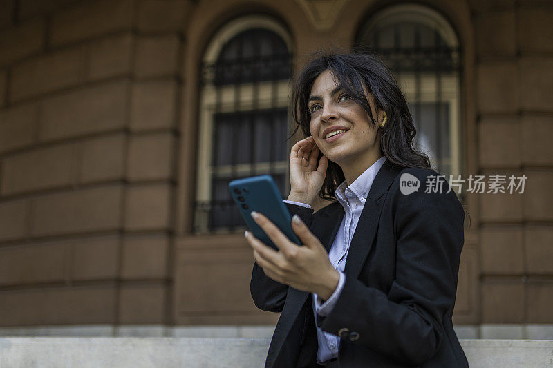 穿着西装的漂亮女孩喜欢戴着耳机和同事聊天