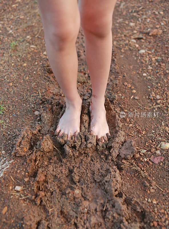 孩子光着脚走在乡下的路上，脚上满是泥。