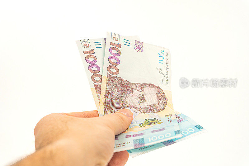 乌克兰现金货币的概念。现金支付在乌克兰。一个人用乌克兰的钱付钱。手里拿着1000格里夫纳，孤立在白底上。乌克兰最大面值的钞票