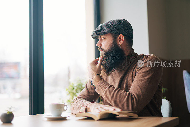 年轻英俊的男子在一家现代化的咖啡馆餐厅看书