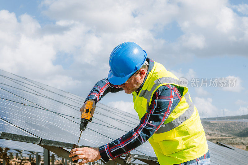 太阳能电池板安装:技术人员在工厂屋顶上与钻机一起工作