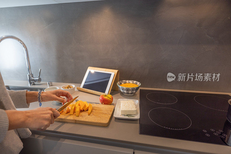 妇女在家里按照数字平板电脑上的食谱准备健康食品