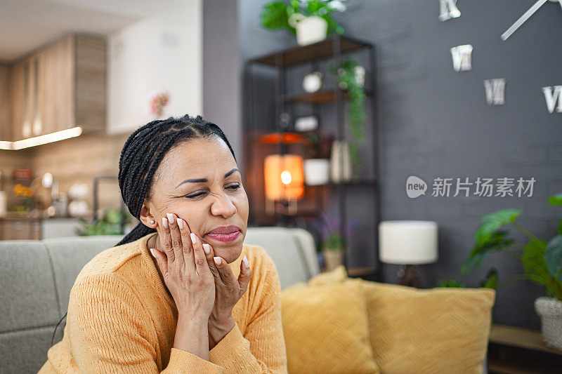 一名黑人妇女牙痛得厉害，在家里用手托着右脸颊