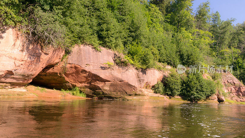 美丽的日子里，河上的沙岩峭壁和树木倒映在水中，蓝天倒映在河水中