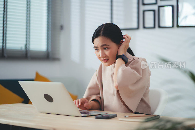 亚洲女性使用笔记本电脑，思考项目，感到困惑。