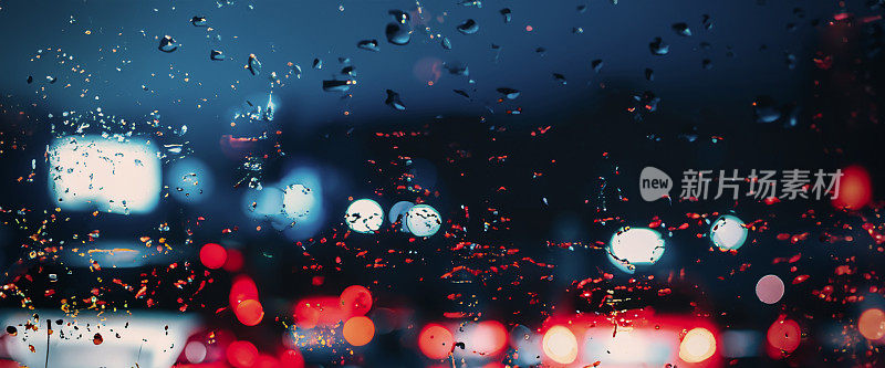 在雨中开车。雨季雨水落在汽车挡风玻璃或车窗上，背景是模糊的交通道路。雨滴落在汽车后视镜上。雨中的路。毛毛雨会降低行车能见度。