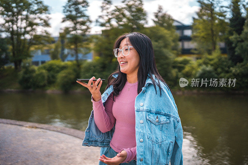 戴眼镜的快乐混血女人在河边用电话与家人聊天