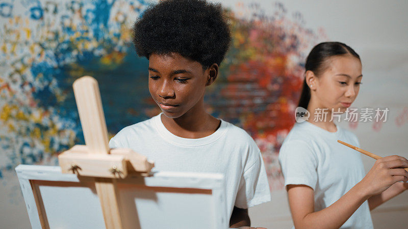 非洲男孩画画布，而女孩画冷色调的画面。启迪。