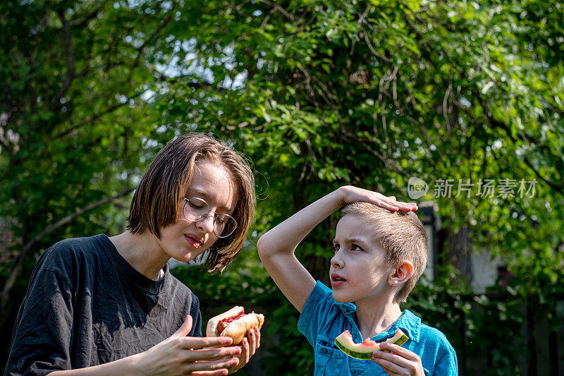 庆祝家庭团聚:性别不一致的青少年和弟弟分享美味的后院大餐