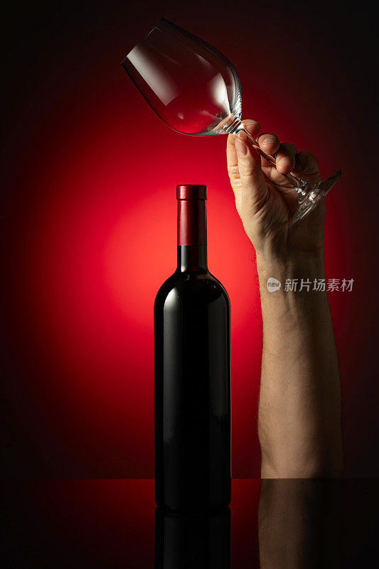 未开瓶的红酒和手握的酒杯。