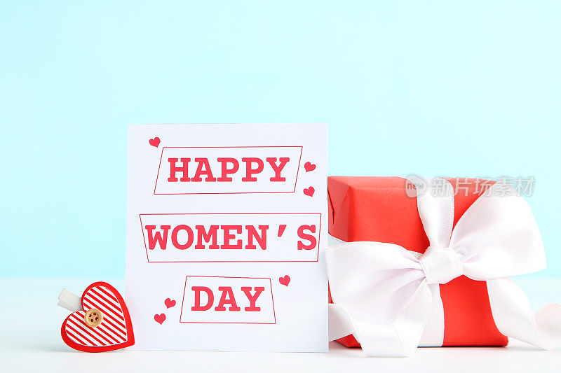 卡片上写着“妇女节快乐”，礼盒和蓝色背景的衣夹形状的心