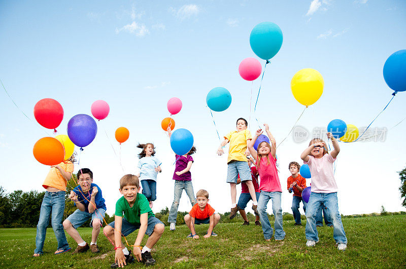 一群兴奋的男孩和女孩用气球庆祝