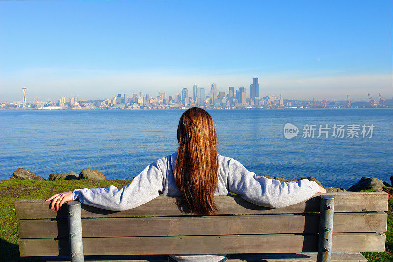 坐在木凳上看城市风景的女人