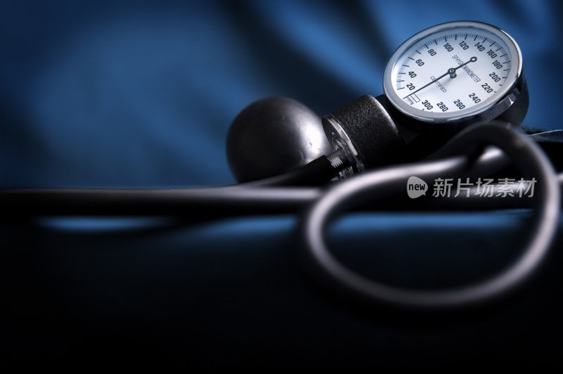 一个血压计躺在蓝色的布上的暗光图片