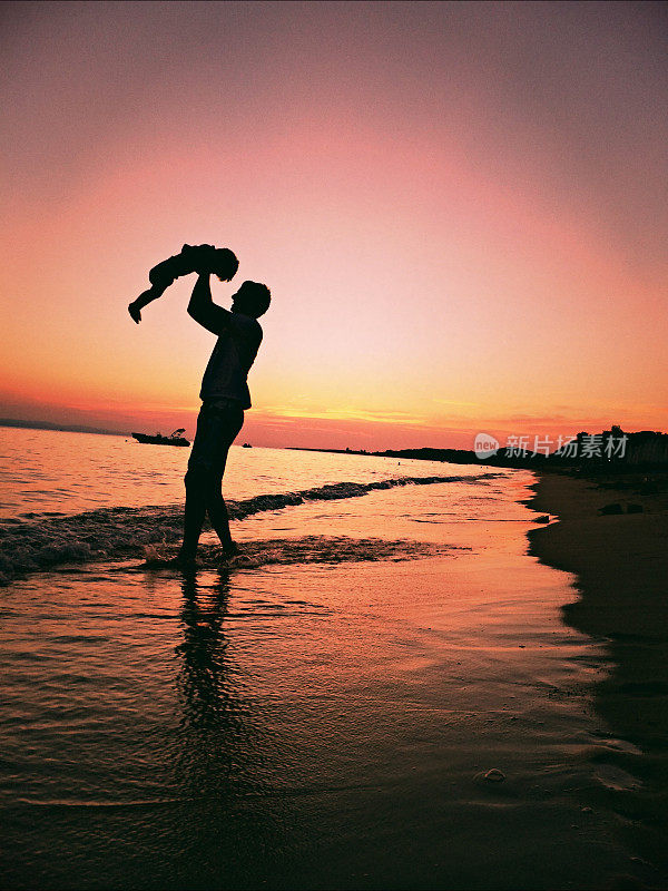 父亲和儿子在海滩上欣赏日落