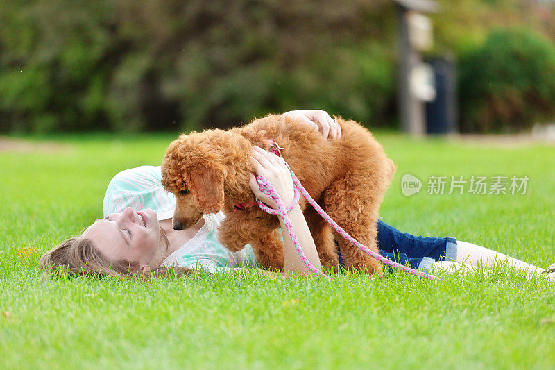 年轻女子在公园里和狮子狗玩耍
