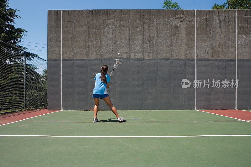 女子对着墙练习长曲棍球